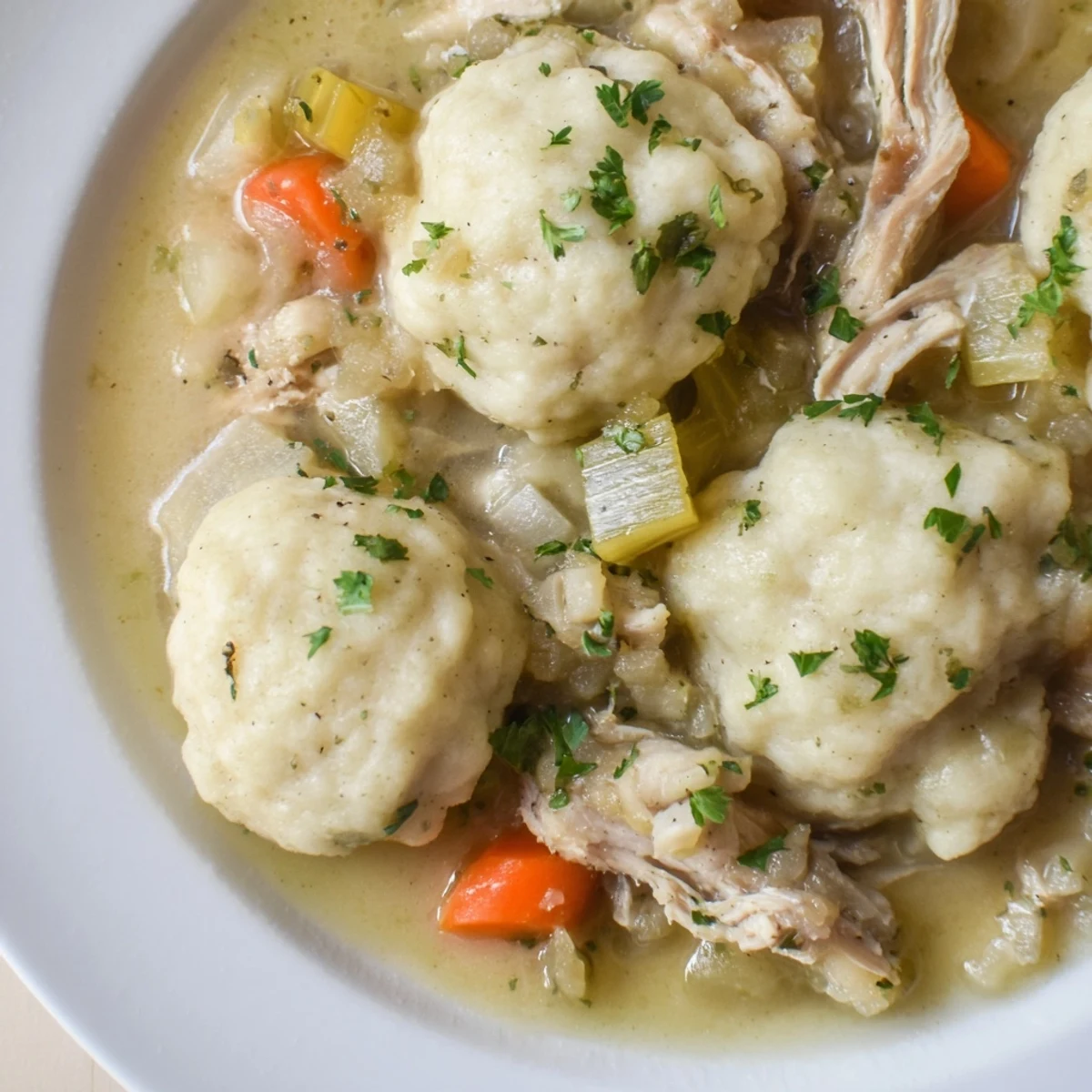 Hearty bowl of Classic Chicken and Dumplings topped with fresh parsley for added flavor.