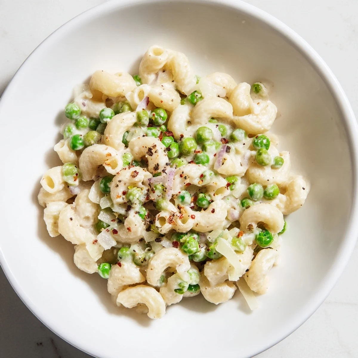 Plate of warm Macaroni & Peas, perfectly cooked macaroni mixed with sweet peas and Parmesan.