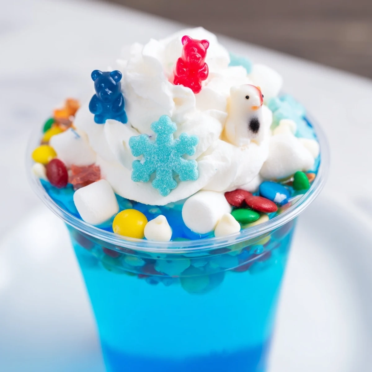 Clear cups filled with layered snow globe Jello, plus white chocolate chips and sprinkles.