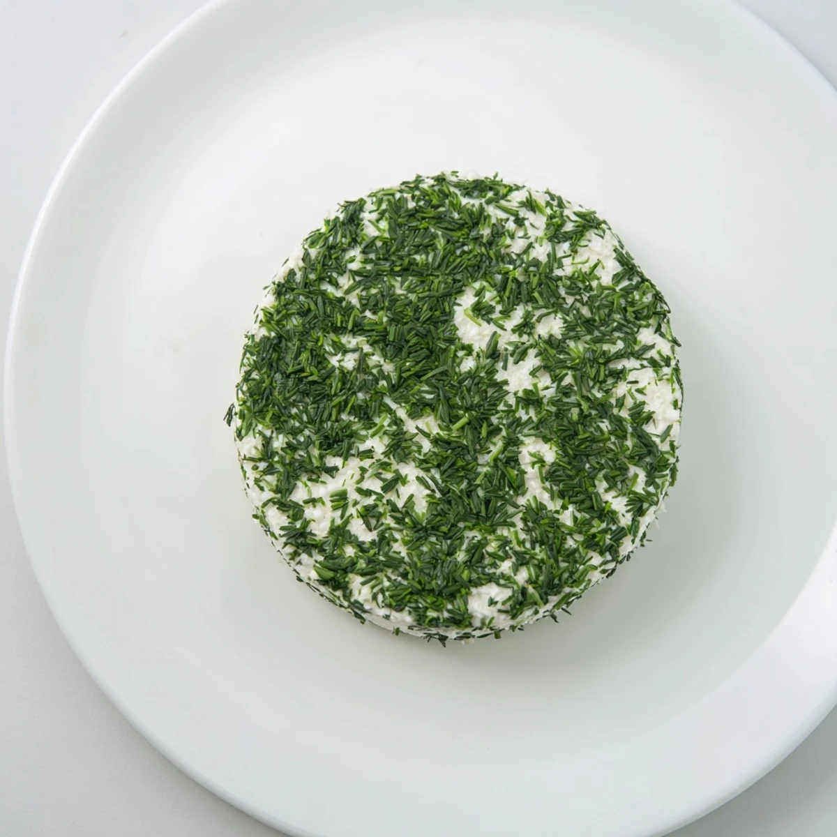 Creamy goat cheese "Mossy Stones" appetizer, rolled in herbs, ready for a cheese platter.