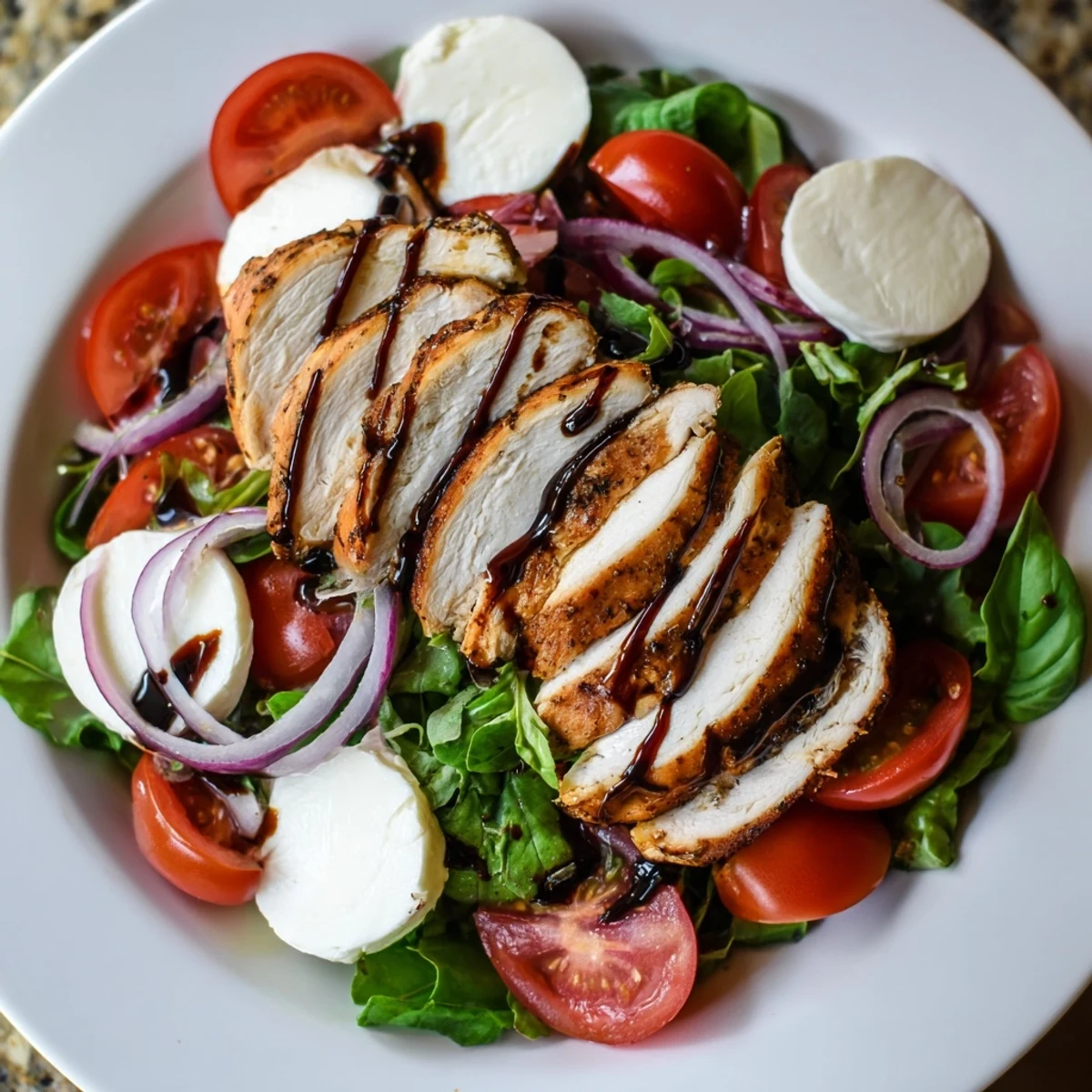 Juicy grilled chicken tops a Caprese Chicken Salad, with fresh basil and balsamic, ready to eat.