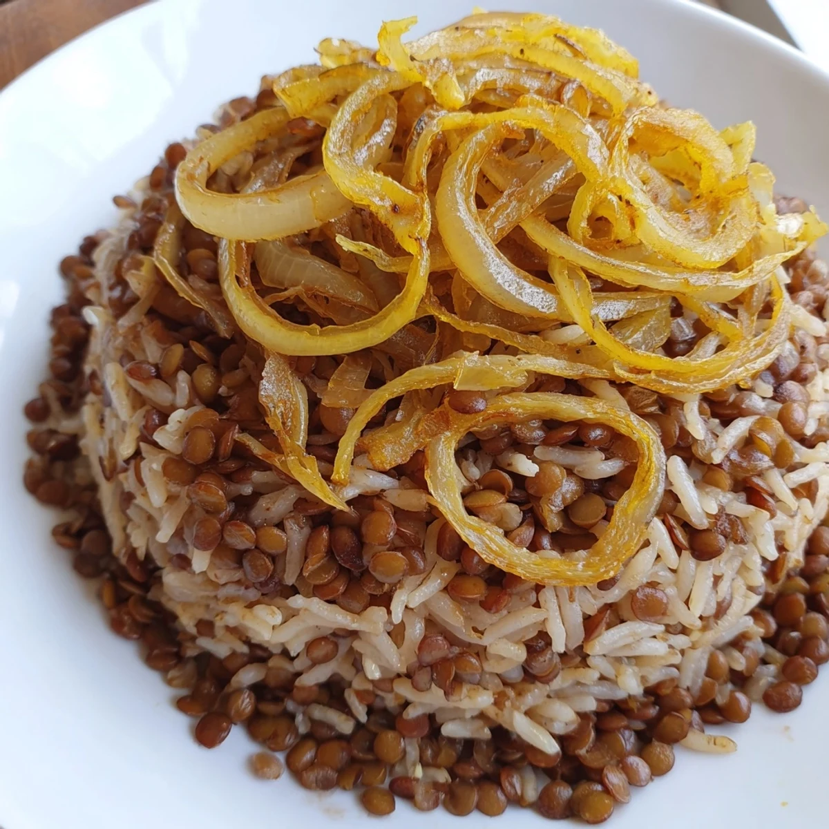 Golden caramelized onions crown a bowl of fragrant Lebanese Mjadra with perfectly cooked lentils and rice.