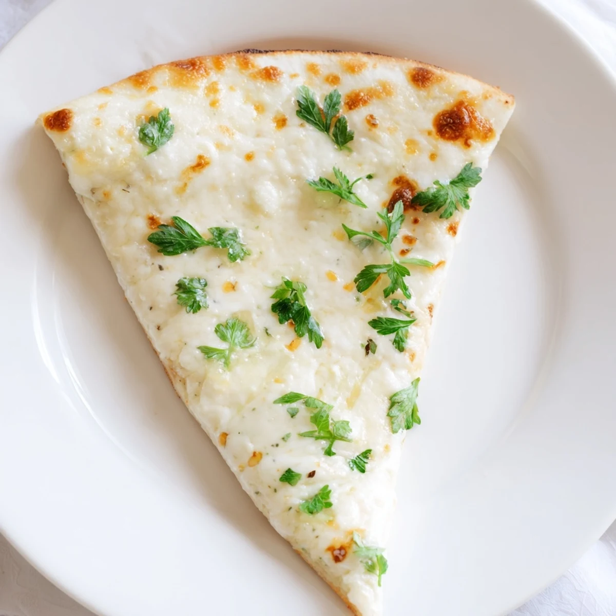 Golden-brown Creamy Garlic White Pizza with bubbling mozzarella and fresh parsley on a wooden board.