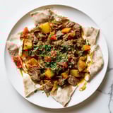 Flavorful Yemeni Saltah, rich meat stew served atop soaked bread, ready for a delicious bite.