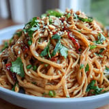 Creamy Thai peanut-lime sauce coats rice noodles, bell peppers, carrots, and cucumber for a refreshing meal.