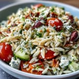 Vibrant orzo salad featuring creamy feta, crisp vegetables, and zesty lemon.