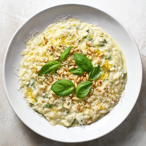 Steaming bowl of 15-Minute Creamy Pesto Risoni with vibrant green pesto and sprinkled Parmesan.