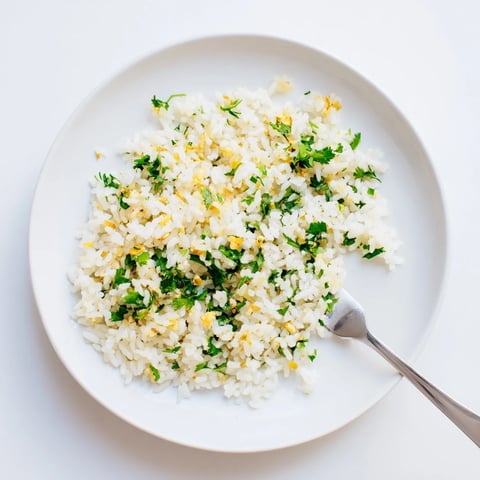A fluffy bowl of homemade Jasmine Rice Garlic, glistening with garlic-infused oil and fresh cilantro garnish.
