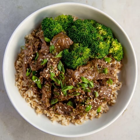 A steaming bowl of Slow-Cooker Beef & Broccoli with fresh greens, a perfect comfort food meal.