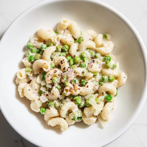 Plate of warm Macaroni & Peas, perfectly cooked macaroni mixed with sweet peas and Parmesan.