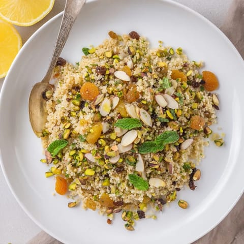 Spiced couscous pilaf with apricots, golden raisins, toasted nuts, and fresh mint, ready to serve as a side dish.