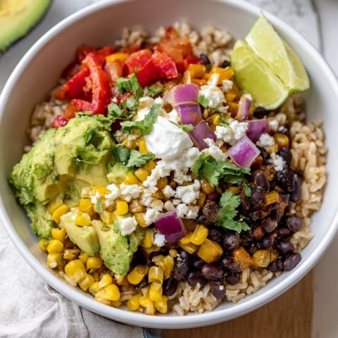 A close-up view of a nutritious Brown Rice Burrito Bowl featuring seasoned black beans, corn, tomatoes, and a dollop of tangy sour cream.  