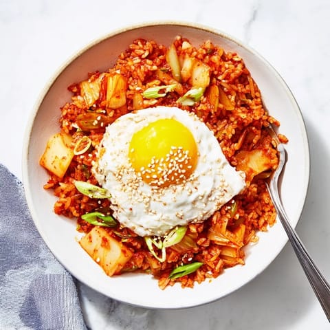 Steaming Kimchi Fried Rice in a skillet, featuring glossy grains coated in gochujang sauce with green onions and diced carrots.