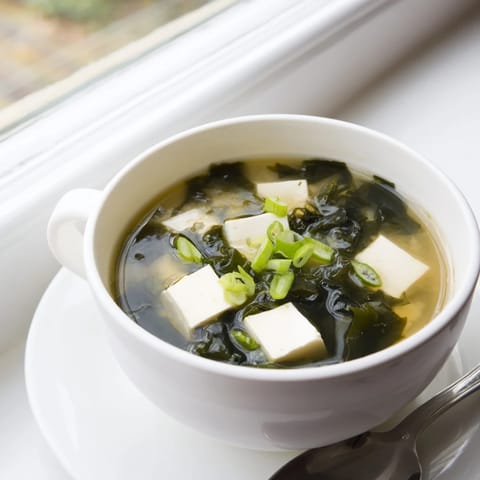 Hearty vegetarian Miso Soup With Tofu features creamy miso broth, delicate seaweed, and warm tofu cubes, served in a rustic ceramic bowl for a nourishing light meal.
