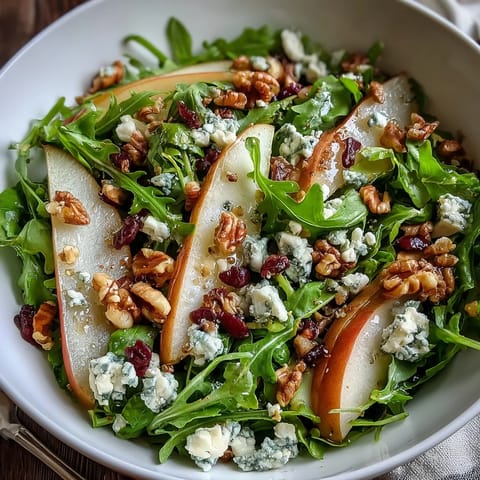 Arugula and Pear Bowl salad tossed with balsamic dressing, served on a white plate ready for a light lunch.