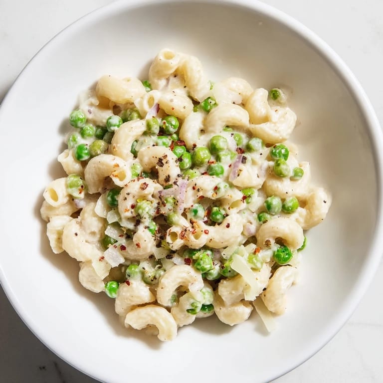 Plate of warm Macaroni & Peas, perfectly cooked macaroni mixed with sweet peas and Parmesan.