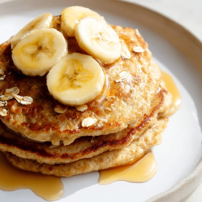 Warm, appetizing pile of banana oat pancakes ready to be devoured with fresh fruit and yogurt.