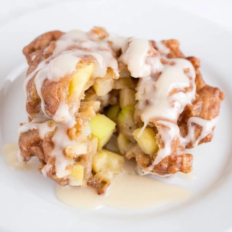 Freshly fried apple fritters, featuring tender apple chunks and a dusting of powdered sugar, are delightful.