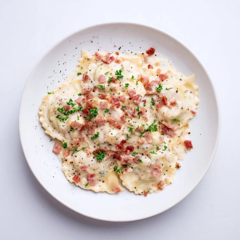 A close-up of Olive Garden Ravioli Carbonara: rich pasta coated in a decadent, savory cream sauce.