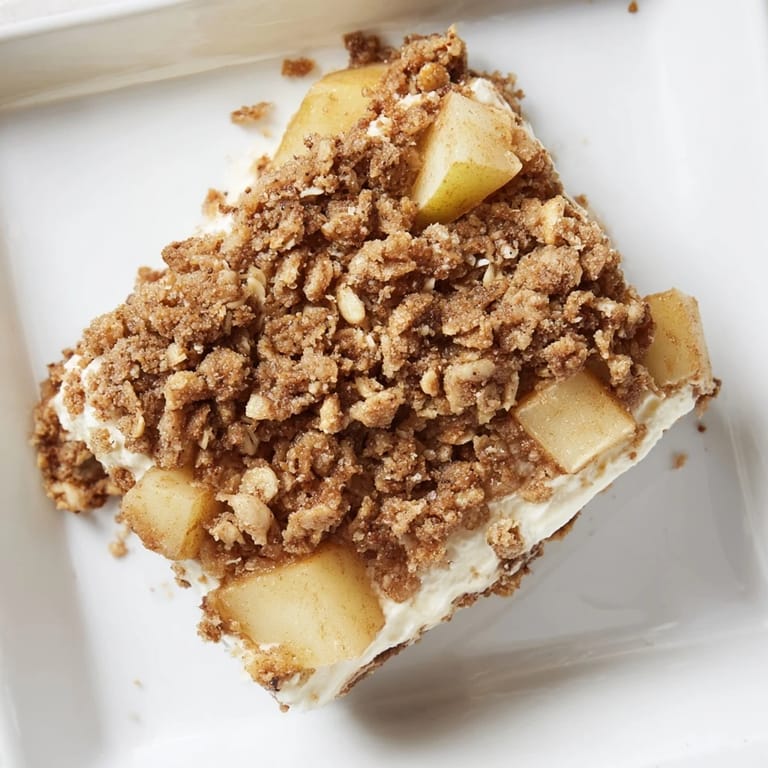 Close-up of freshly baked Apple Crisp Cheesecake Bars, showing layers of creamy cheese and apples.