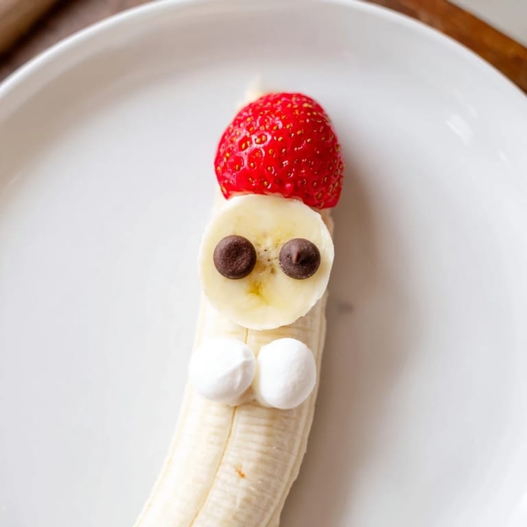 Homemade Banana Strawberry Santa Skewers offer a delightful snack, showcasing Santa's face with chocolate eyes and marshmallow hats.