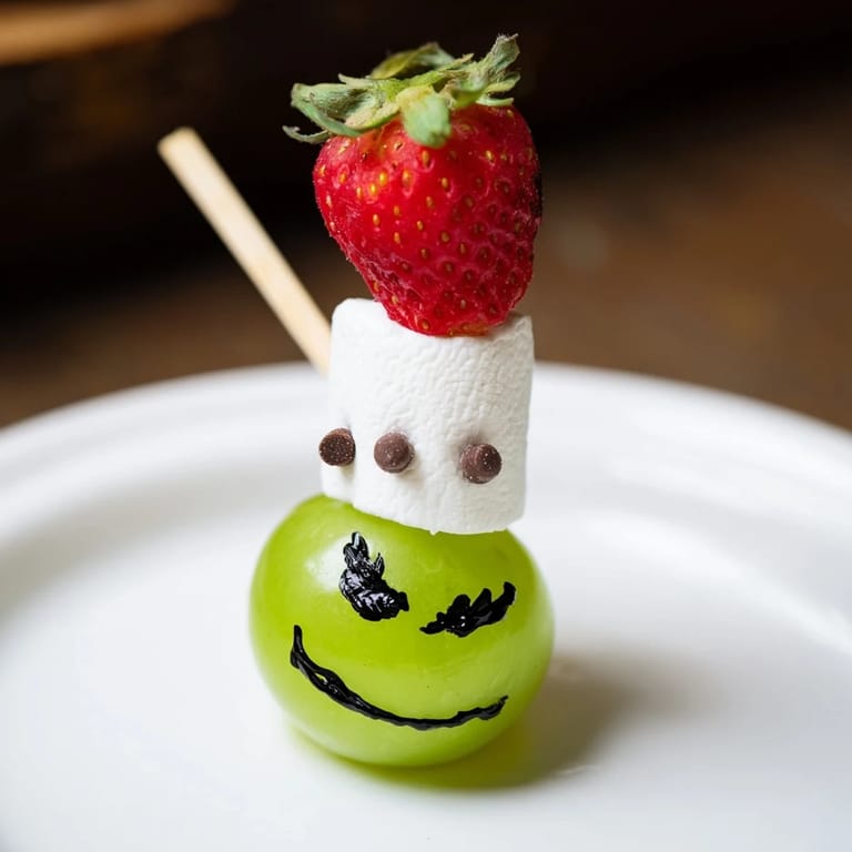 Kid-friendly Grinch snack features cheerful Grinch faces using fresh green grapes and fruit.