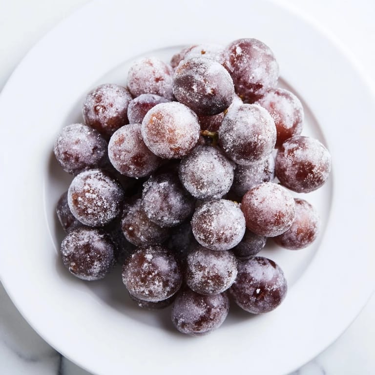 Vibrant red and green Frozen Grapes glimmering on a baking sheet, a refreshing, healthy treat idea.