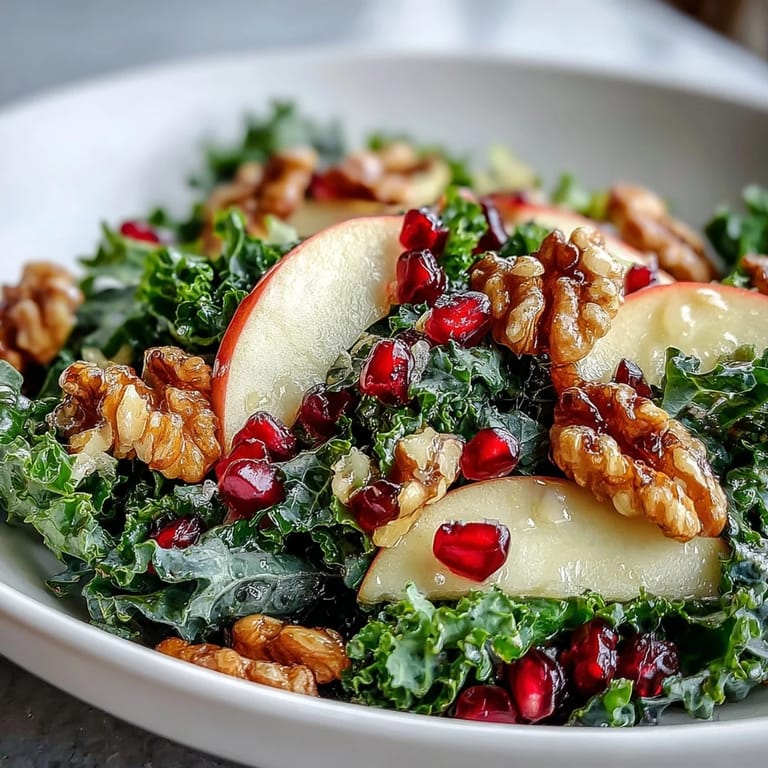 Colorful healthy salad featuring tender kale, juicy pomegranate arils, crunchy nuts, and fresh apple slices ready to eat.
