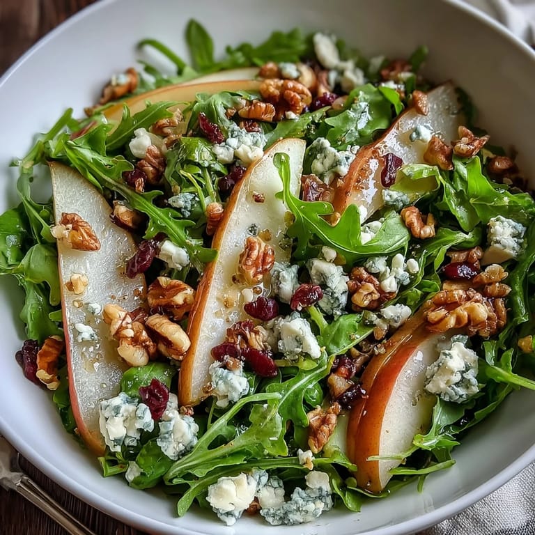 Arugula and Pear Bowl salad tossed with balsamic dressing, served on a white plate ready for a light lunch.