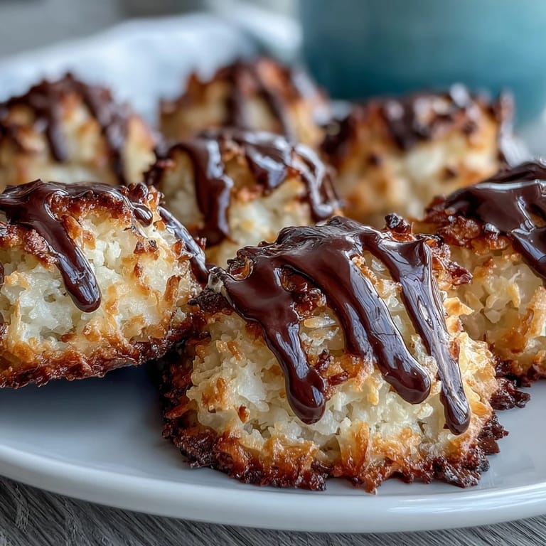Vegan Coconut Macaroons with Dark Chocolate Drizzle glisten on a ceramic plate.