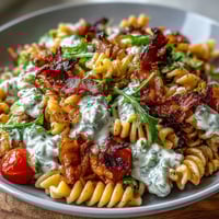 Creamy BLT pasta salad with bacon, avocado, and cherry tomatoes in a tangy lemon-Dijon dressing, perfect for summer gatherings.  